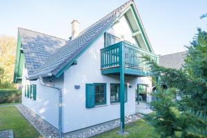 a white house with green shutters and a balcony at Ferienwohnung Lee West 2 3 in Dierhagen