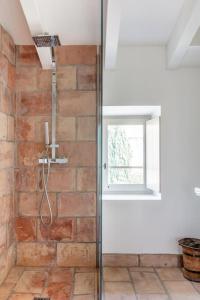 een badkamer met een glazen douche en een bakstenen muur bij La Demeure Provençale au charme suranné in Nîmes