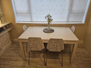 a table with two chairs and a vase with flowers on it at Leigh-on-Sea Retreat - 2 Bedroom Apartment in Leigh-on-Sea