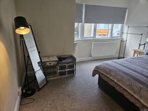 a bedroom with a bed and a lamp and a window at Leigh-on-Sea Retreat - 2 Bedroom Apartment in Leigh-on-Sea