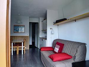 ein Wohnzimmer mit einem Sofa und roten Kissen in der Unterkunft Studio Les Menuires, 1 pièce, 4 personnes - FR-1-344-1050 in Les Menuires