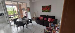 uma sala de estar com um sofá preto e uma mesa em Apto Ubatuba Home - Eloisa 114 em Ubatuba