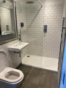 a bathroom with a toilet and a tub and a sink at The Angler, Oakham in Oakham