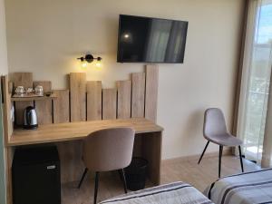 ChaourceにあるLogis Le Cadusiaの木製デスク、椅子2脚、テレビが備わる客室です。