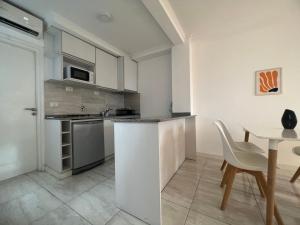 Una cocina con gabinetes blancos y una mesa y sillas. en Céntrico mono ambiente completo y amplio, en Santa Fe