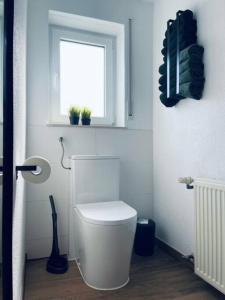biała łazienka z toaletą i oknem w obiekcie Ferienwohnung Hilda w mieście Uttenweiler