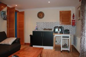 een woonkamer met een kleine keuken en een tv bij 73 Westend, Balallan, Isle of Lewis in Balallan