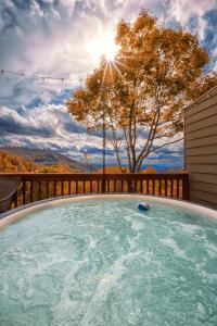 a hot tub on a deck with a tree and the sun at Hibernation Station - MTN Views near Asheville! in Swiss