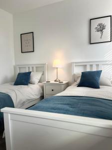 two beds with blue pillows in a bedroom at Newly Renovated 3 Bedroom Victorian Detached House in Bournemouth