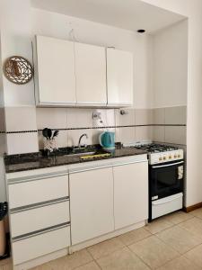 cocina blanca con armarios blancos y fogones en Departamento Nórdico San Juan en San Juan