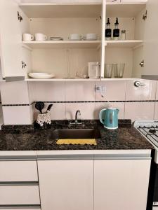 a kitchen with white cabinets and a sink at Departamento Nórdico San Juan in San Juan
