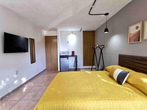 a bedroom with a large yellow bed and a kitchen at Estudio 2 personas en el Centro/agencias aduanales in Veracruz