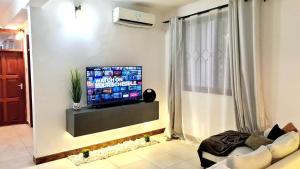 sala de estar con TV de pantalla plana en la pared en Luxurious apartment with King size bed, en Dar es Salaam