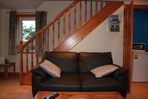un sofá de cuero en una sala de estar con una escalera en 73 Westend, Balallan, Isle of Lewis en Balallan