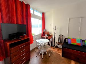 ein Wohnzimmer mit einem TV und einem Tisch mit einem Stuhl in der Unterkunft Sala Living Frente ao Mar in São Vicente