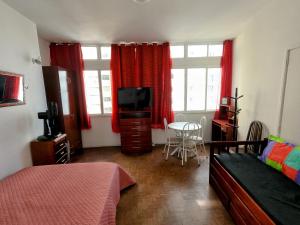 Schlafzimmer mit einem Bett, einem TV und einem Tisch in der Unterkunft Sala Living Frente ao Mar in São Vicente