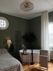 a bedroom with a bed and a tub and a chandelier at Pastors Prästgården in Norberg