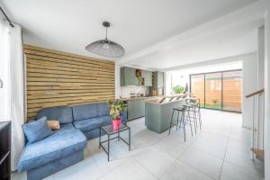 a living room with a blue couch and a kitchen at Maison rénové proche Paris 15. in Malakoff