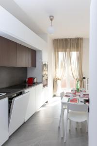 cocina blanca con mesa blanca y sillas en Exclusive Guest House - Fiera Milano Rho, en Rho