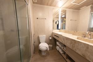 a bathroom with a toilet and a glass shower at Spa do Vinho Condomínio Vitivinícola in Bento Gonçalves