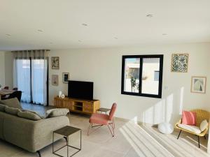 un soggiorno con un divano e una TV di La Maison Louis - moderne & familiale a Lapalme