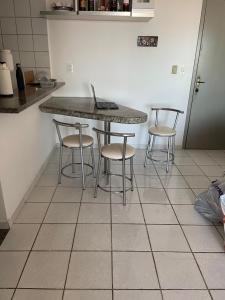 eine Küche mit einer Theke mit Hockern und einem Tisch in der Unterkunft Apartamento com Vista para o Mar in Conceição da Barra