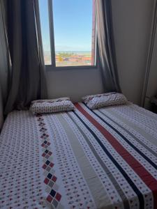 Bett in einem kleinen Schlafzimmer mit Fenster in der Unterkunft Apartamento com Vista para o Mar in Conceição da Barra