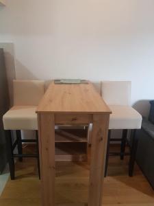 una mesa de madera con 2 sillas blancas y una mesa con un cajón en Lady en Banja Luka