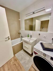 a white bathroom with a sink and a bath tub at Dizajnový Apartmán - Tehelné Pole - free parking in Bratislava
