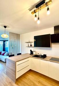 a kitchen with white cabinets and a living room at Dizajnový Apartmán - Tehelné Pole - free parking in Bratislava
