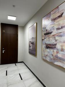 einen Flur mit zwei Gemälden an der Wand und einer Tür in der Unterkunft 4YOU апартаменты in Almaty