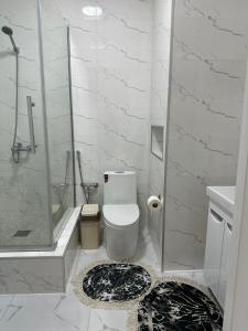ein weißes Bad mit einer Dusche und einem WC in der Unterkunft 4YOU апартаменты in Almaty