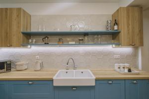 a kitchen with blue cabinets and a white sink at Minoos Residence with roof pool in Rethymno Town