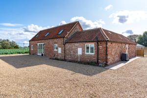 a brick house with a gravel driveway at The Roost and The Nook Rural Barn Stays in Quadring