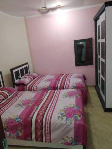 2 camas en un dormitorio con paredes rosas en كمبوند سيبريا en Hurghada