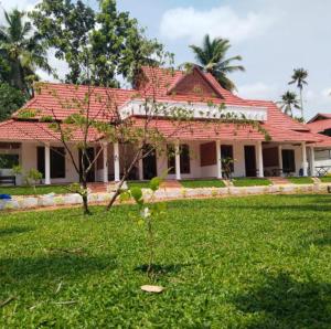 a house with a red roof and a green yard at The Royal Island in Munroe Island