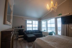 a bedroom with a bed and a couch and a chandelier at Mörk Superior Cottages in Hvammstangi