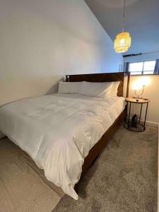 a bedroom with a large bed with white sheets and a lamp at San Diego Gaslamp Loft Getaway in San Diego
