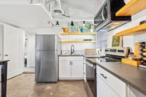 a kitchen with white cabinets and a stainless steel refrigerator at The River Box - Luxury Container Home - views and Hot Tub in Yakima
