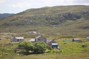 un gruppo di case in un campo con una collina di 73 Westend, Balallan, Isle of Lewis a Balallan