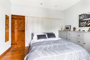 a white bedroom with a bed and a wooden floor at Little Braybrooke Cottage in Saffron Walden