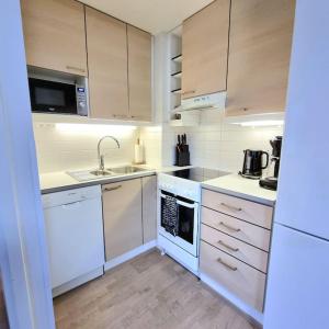 una cocina con electrodomésticos blancos y armarios blancos en Moderni kaksio keskustassa, oma sauna!, en Uusikaupunki