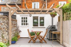 a patio with a table and a wooden pergola at Little Braybrooke Cottage in Saffron Walden