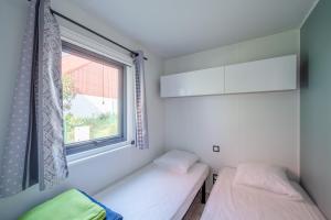 two beds in a room with a window at Camping de Saverne in Saverne