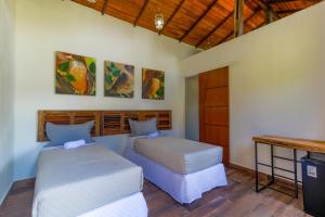 1 dormitorio con 2 camas, mesa y escritorio en Art Green Teresópolis en Teresópolis