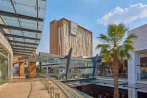 ein Einkaufszentrum mit einer Palme und einem hohen Gebäude in der Unterkunft City Express Plus by Marriott Mundo E in Mexiko-Stadt
