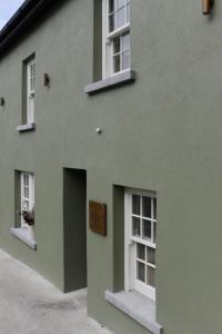 a green building with white windows and a door at WITHIN THE VILLAGE in Galway
