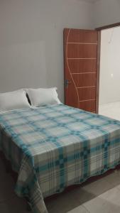 a bedroom with a bed with a blue plaid blanket at Sua casa completa em Viçosa do Ceará in Viçosa do Ceará