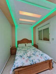 Schlafzimmer mit einem Bett mit grüner Decke in der Unterkunft Apprtemment Sala Al Jadida in Oulad Yakoub