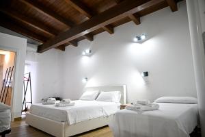 2 łóżka w pokoju z białymi ścianami i drewnianymi sufitami w obiekcie Borgo Caridà - Green Family Holidays w mieście Zaccanopoli